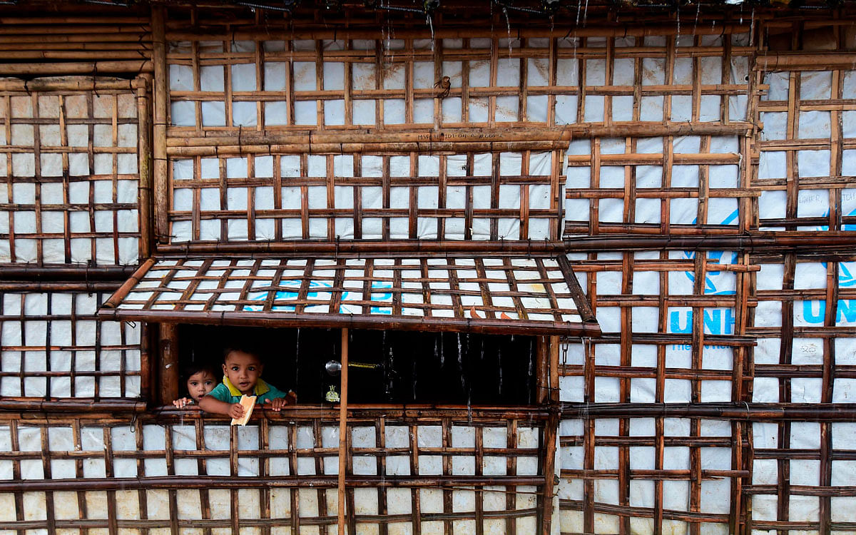 Rohingya refugee children look out from their makeshift house during a monsoon rainfall at Kutupalong refugee camp in Ukhia on 12 Setember 2019. Photo: AFP