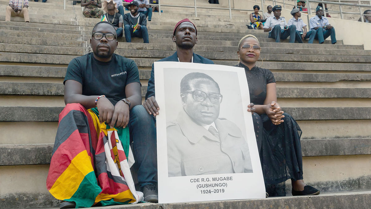 A man holds a portrait of Zimbabwe`s late president Robert Mugabe during his official funeral ceremony at the National Sports stadium in Harare, on 14 September 2019. Photo: AFP