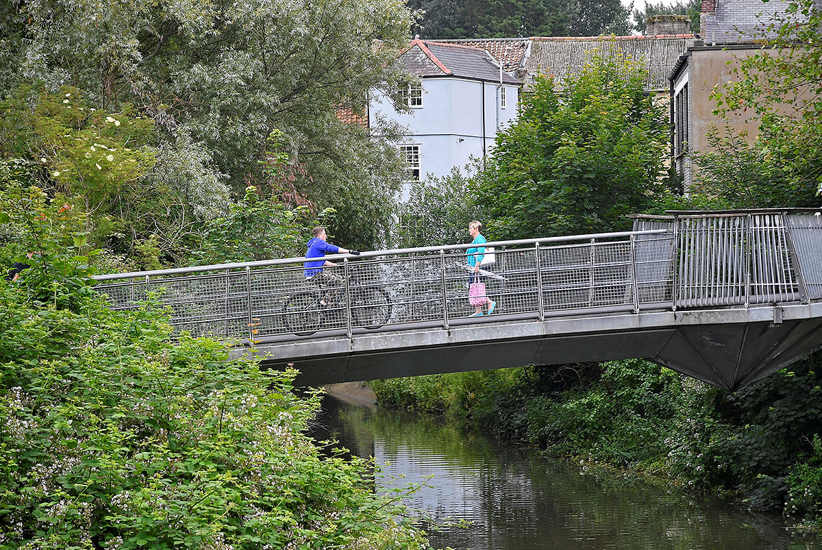 Locals cross a pedestrian bridge over the River Frome in Frome, Britain. Picture taken 25 June 2019. Photo: Reuters