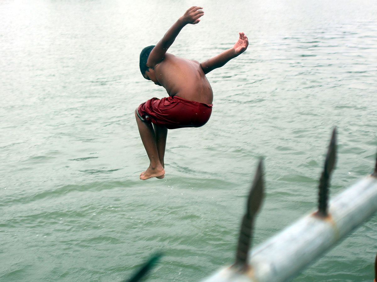 A child jumps into a pond from an iron pipe at Nogua, Kishoreganj. 15 September 2019. Photo: Tafsilul Aziz