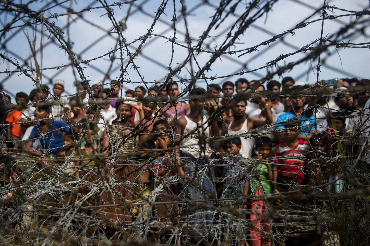 In this file photo taken on 25 April, 2018, taken from Maungdaw district, Myanmar`s Rakhine state shows Rohingya refugees gathering behind a barbed-wire fence in a temporary settlement setup in a `no man`s land` border zone between Myanmar and Bangladesh. Photo: AFP