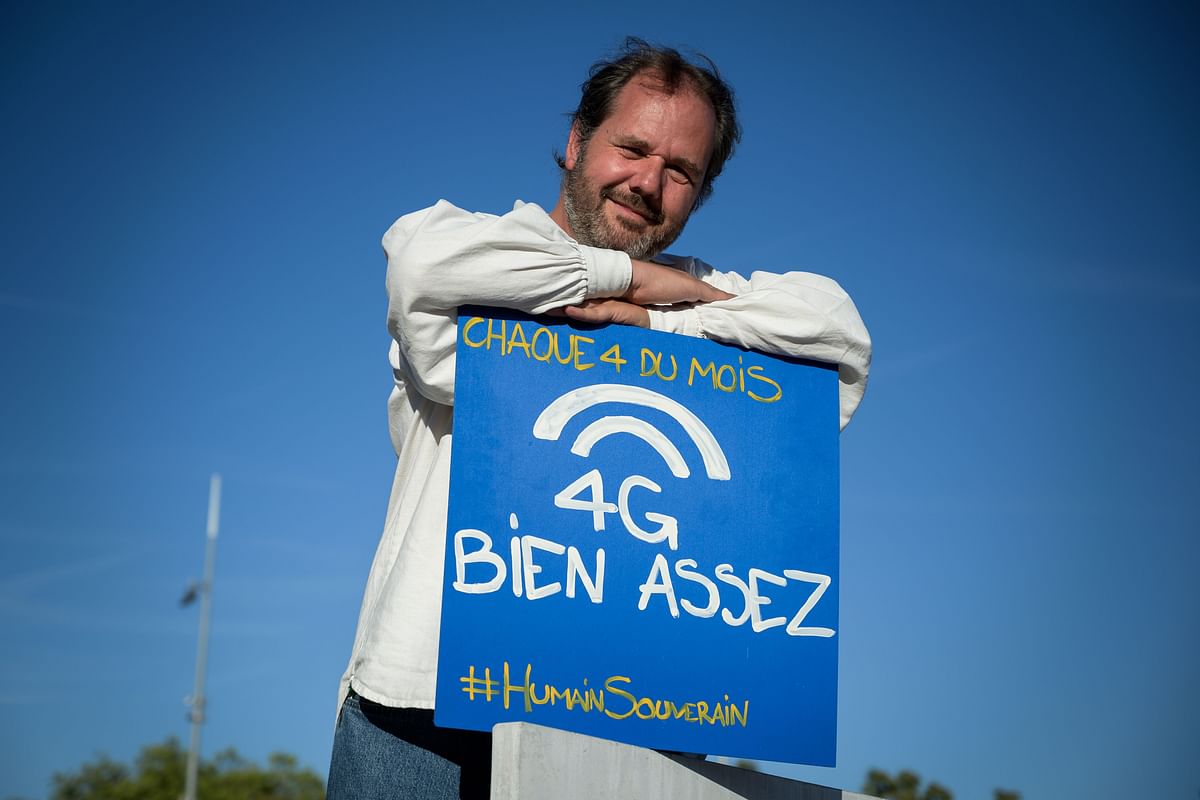 Opponent of the deployment of antennas for the 5G mobile network service, Swiss Olivier Pahud, holds a placard reading `4G good enough` during a protest staged the four of each month in Geneva, on 4 September 2019. Photo: AFP