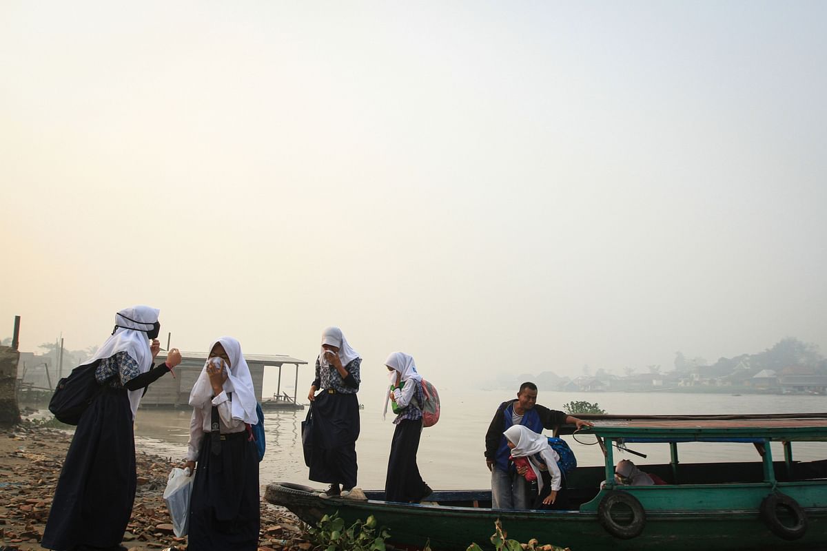 A group of Indonesian Muslims cover their faces as they disembark from a boat on a hazy day in Palembang on 18 September 2019. Photo: AFP