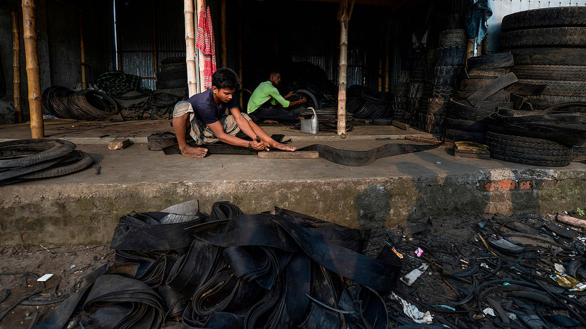 Labourers cut pieces of used tyres in Dhaka on 1 September 2019. Photo: AFP