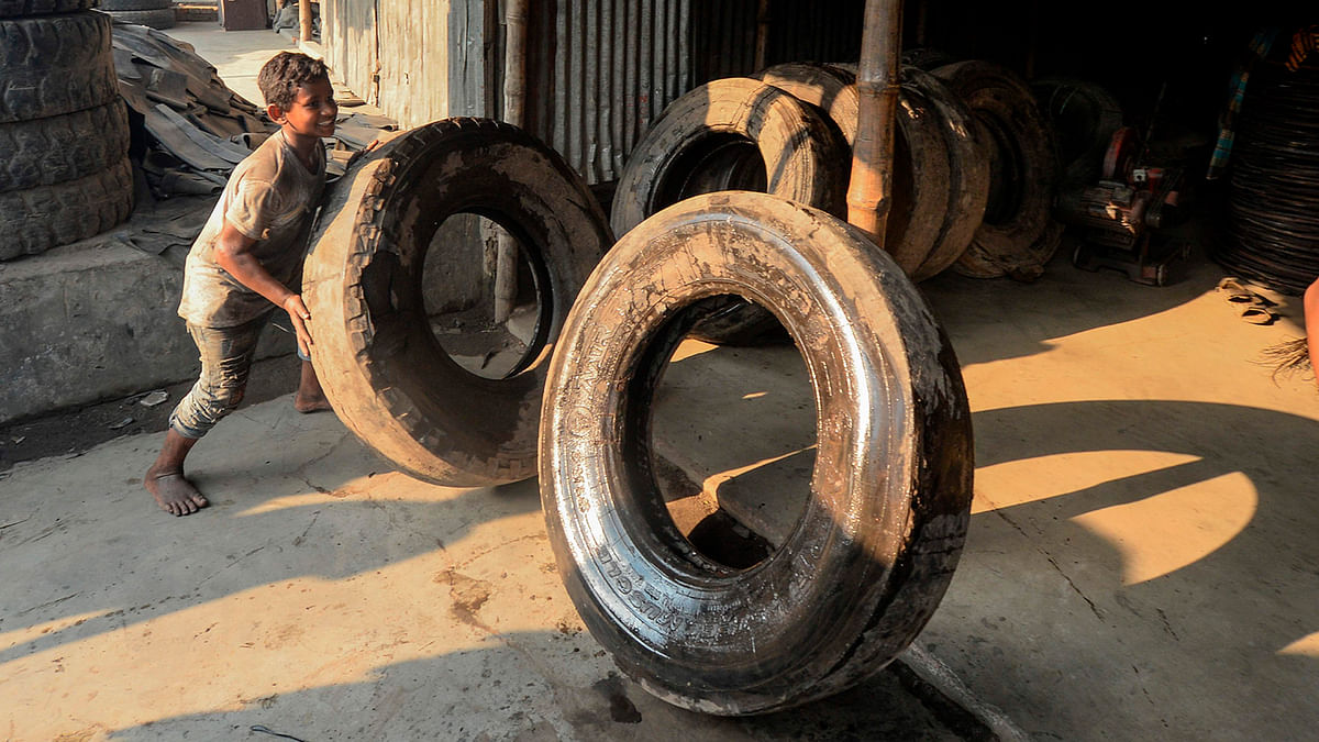 A young labourer handles old tyres in Dhaka on 1 September 2019. Photo: AFP