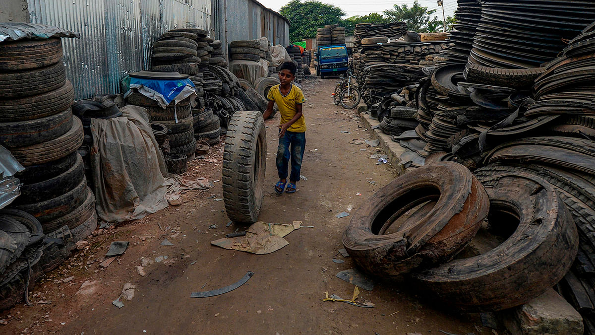 A young labourer handles an old tyre in Dhaka on 1 September 2019. Photo: AFP
