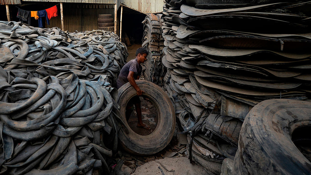 A young labourer handles pieces of an old tyre in Dhaka on 1 September 2019. Photo: AFP