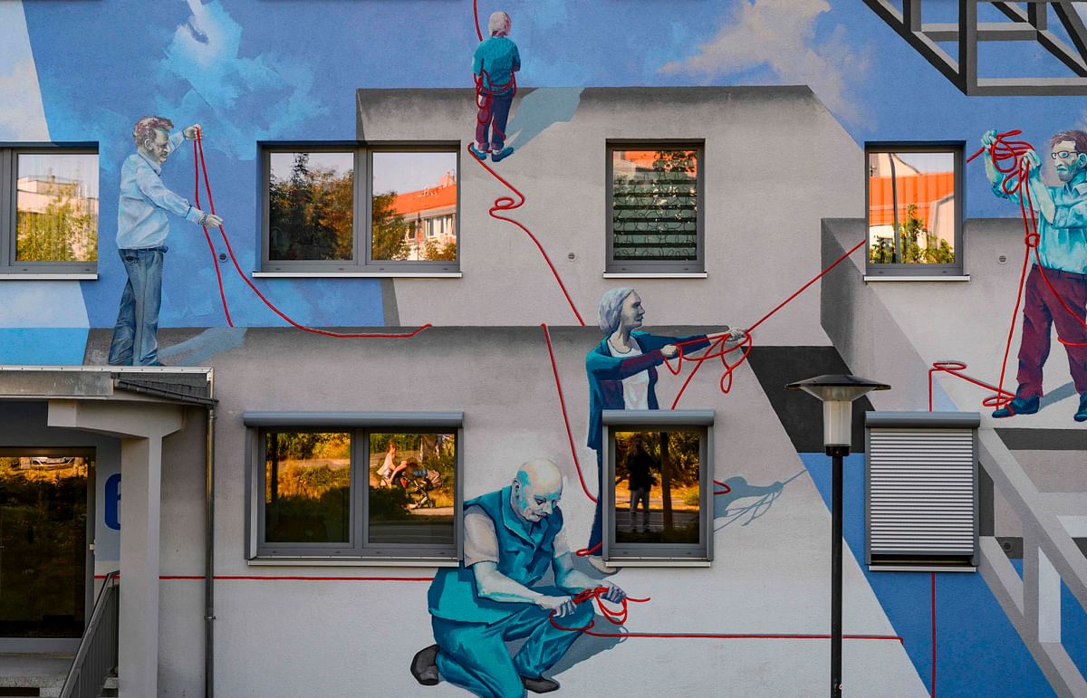 A giant mural by the urban art collective `Freiraumgalerie`, which features likenesses of real people, decorates a residential building owned by the HWG housing company in Halle on 22 August 2019. Photo: AFP