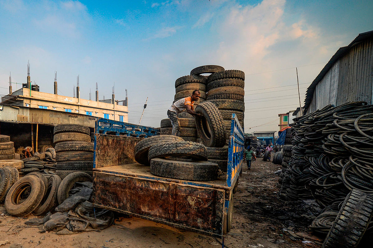 A labourer unloads used tyres from a truck in Dhaka on 19 September, 2019. Photo: AFP