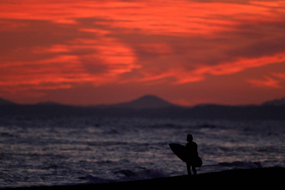 A surfer looks out to the ocean after coming back to the beach after sunset at Nakatajima Sand Dunes near Hamamatsu on 19 September. AFP File Photo