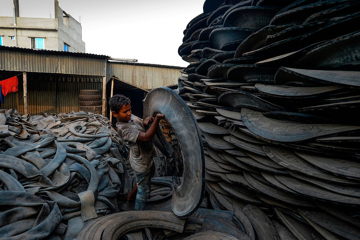 A young labourer handles pieces of an old tyre in Dhaka on 19 September, 2019. Photo: AFP