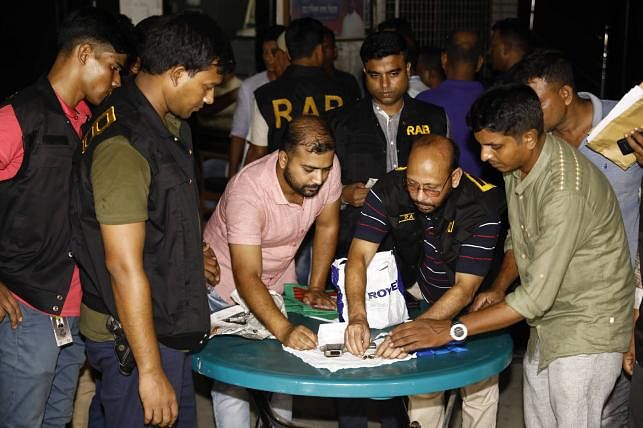 RAB men oversee the coins used in gambling, 572 packets of cards, a foreign-made pistol, bullets and yaba pills they have recovered from Kalabagan Krira Chakra’s office in Dhaka on 20 September 2019. Photo: Shuvra Kanti Das