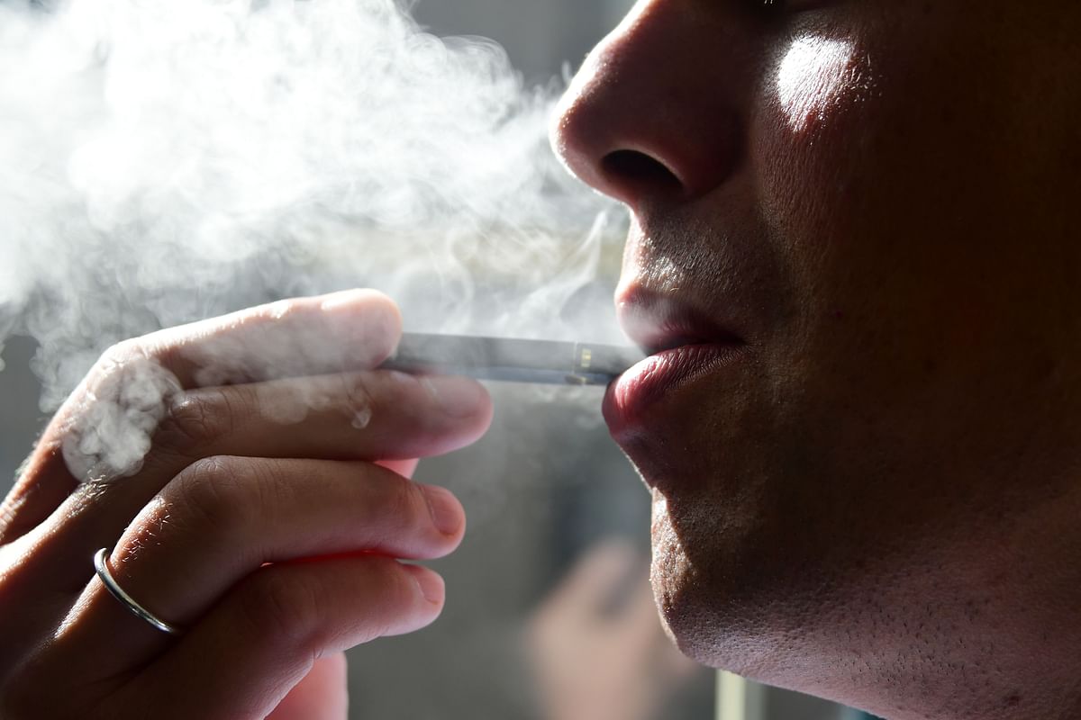 This file photo taken on 2 October 2018 shows a man exhaling smoke from an electronic cigarette in Washington, DC. New York became the second US state to ban flavored e-cigarettes Tuesday, following several deaths linked to vaping that have raised fears about a product long promoted as less harmful than smoking. Photo: AFP