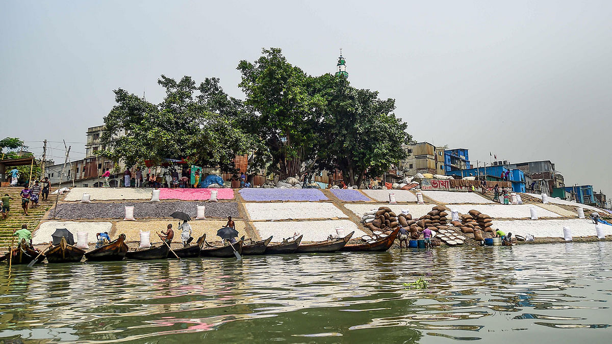 Workers dry recycled plastic chips as boat men wait for passengers in Buriganga river in Dhaka on 22 September 2019. Photo: AFP