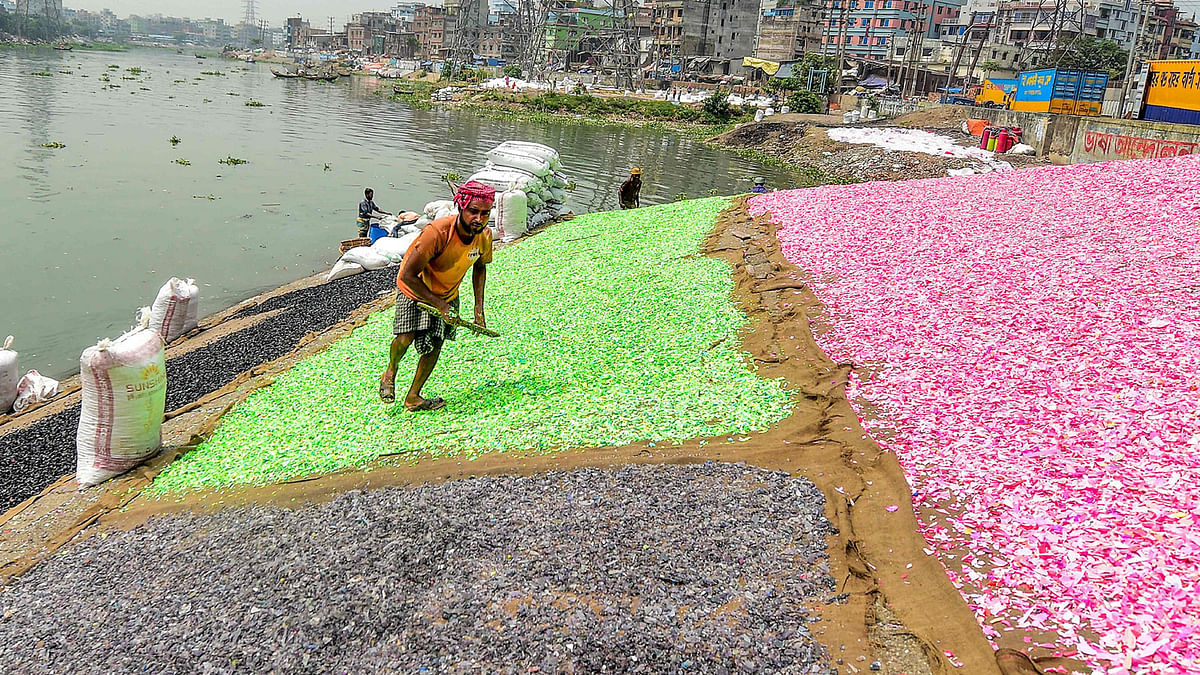 Workers dry recycled plastic chips on the banks of Buriganga River in Dhaka on 22 September, 2019. Photo: AFP