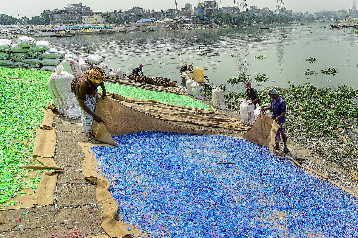 Workers dry recycled plastic chips on the banks of Buriganga river in Dhaka on 22 September 2019. Photo: AFP