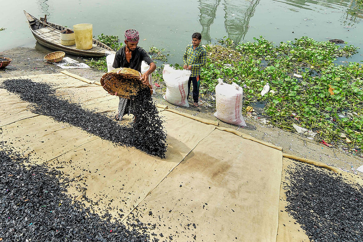 Workers clean recycled plastic chips on the banks of Buriganga river in Dhaka on 22 September 2019. Photo: AFP