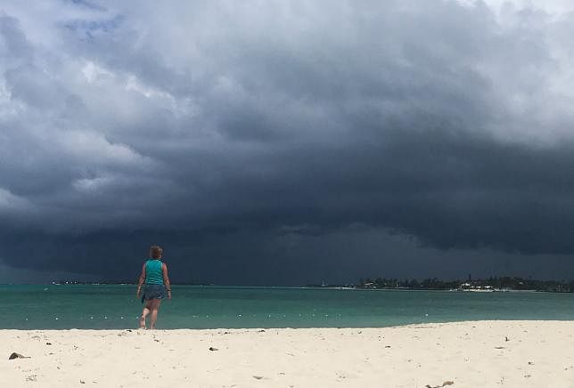 A woman walks on the beach as a storm approaches in Nassau, Bahamas, on 12 September 2019. AFP File Photo