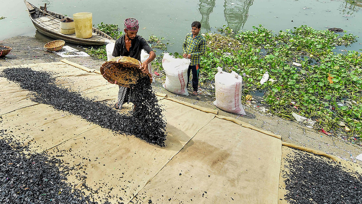 Workers clean recycled plastic chips on the banks of Buriganga River in Dhaka on 22 September, 2019. Photo: AFP