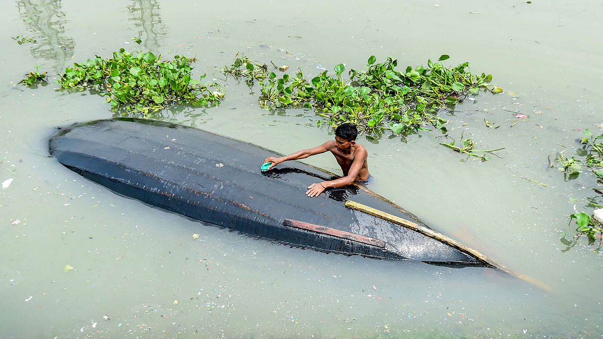 A man cleans his boat in Buriganga River in Dhaka on 22 September, 2019. Photo: AFP