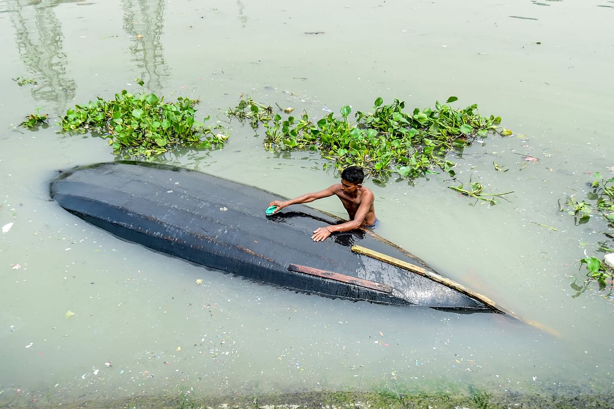 A man cleans his boat in Buriganga river in Dhaka on 22 September 2019. Photo: AFP