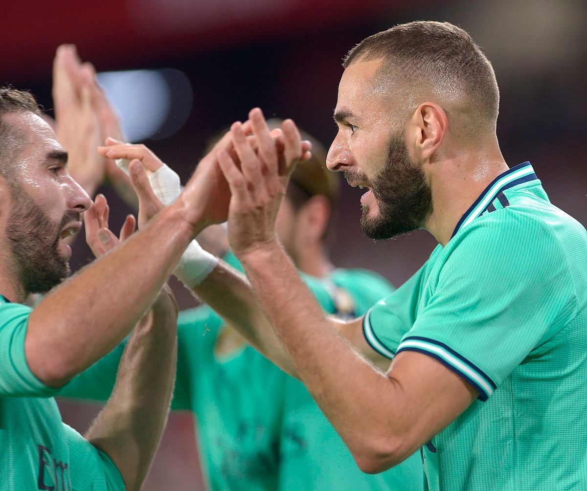Real Madrid`s French forward Karim Benzema (R) celebrates after scoring a goal during the Spanish league football match between Sevilla FC and Real Madrid CF at the Ramon Sanchez Pizjuan stadium in Seville on Sunday. Photo: AFP