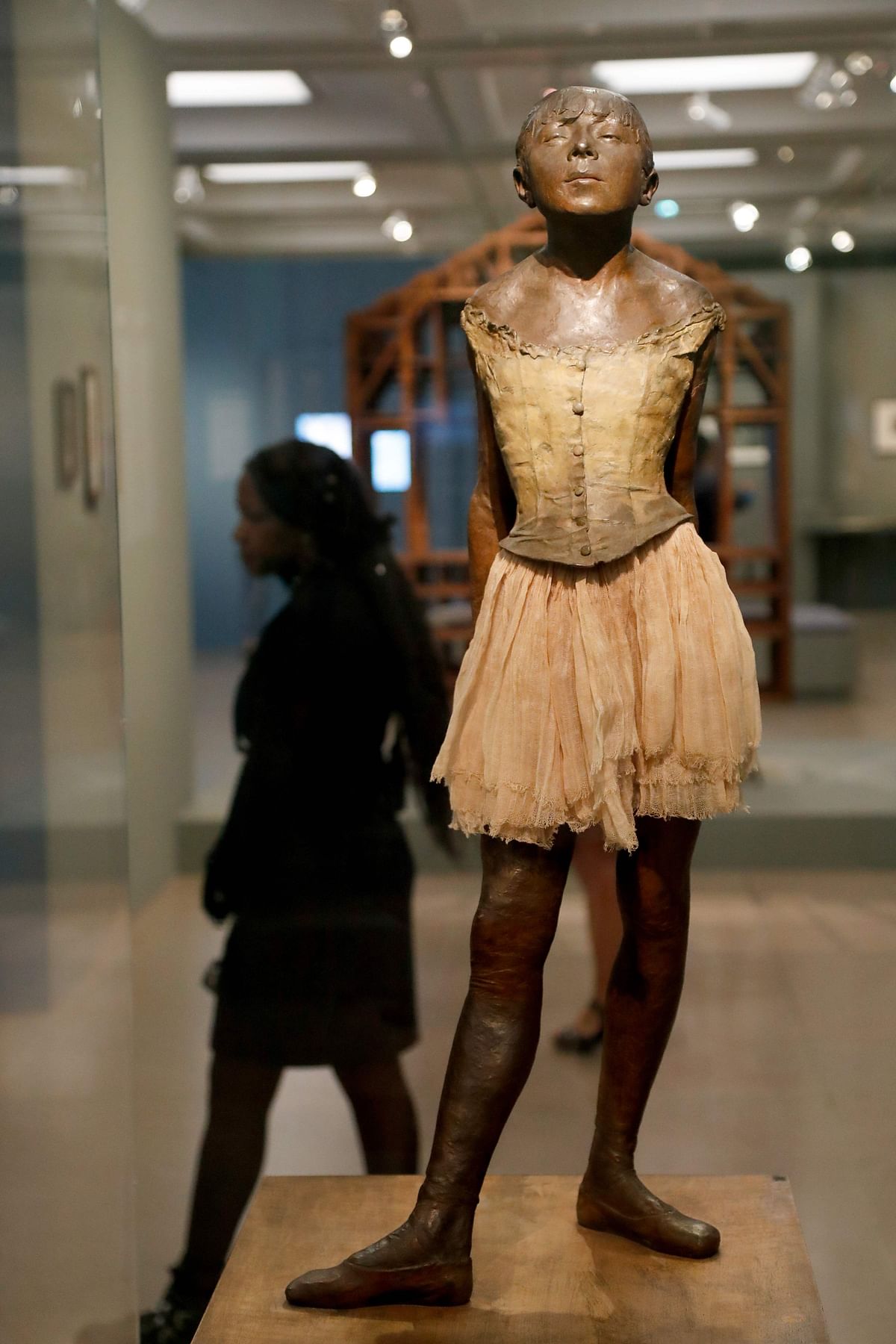 A woman walks behind a bronze statue entitled `Little dancer of 14 years old` (Petite danseuse de 14 ans) made around 1878 - 1880 by French painter Edgar Degas, during the press visit of the exhibition `Degas at the Opera` at the Museum of Orsay, in Paris. Photo: AFP