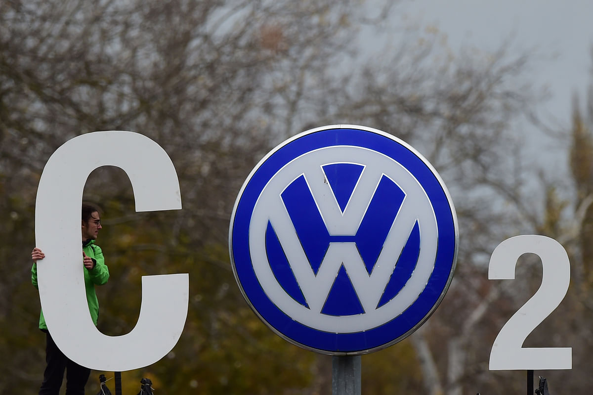 In this file photo taken on 9 November 2015, an activist of environmental organisation Greenpeace holds a giant letter to display `CO2` around the logo of German car maker Volkswagen (VW) at the entrance of the company`s headquarters in Wolfsburg, northern Germany. Photo: AFP