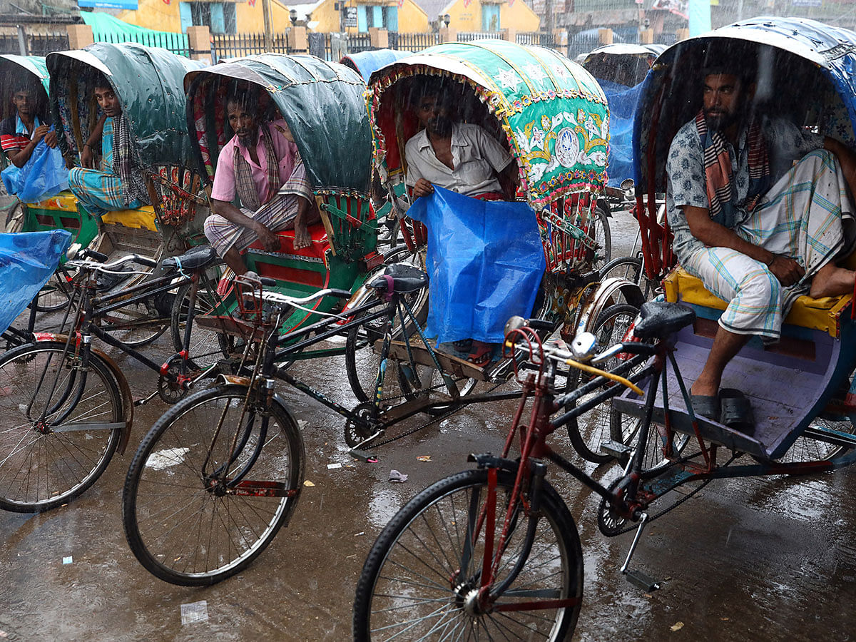 Rickshaw pullers take shelter inside their rickshaws during rain in Dhaka, Bangladesh, 25 September 2019. Photo: Reuters