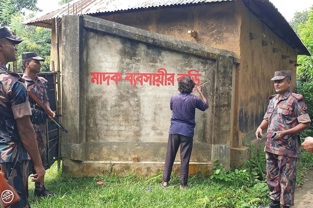 In this photo take on 23 September, 2019 shows Bangladesh border guards watching as a home allegedly belonging to a suspected drug trafficker is marked with red paint -- which reads `This is a house of a drug trafficker` -- in Akhaura. Photo: AFP