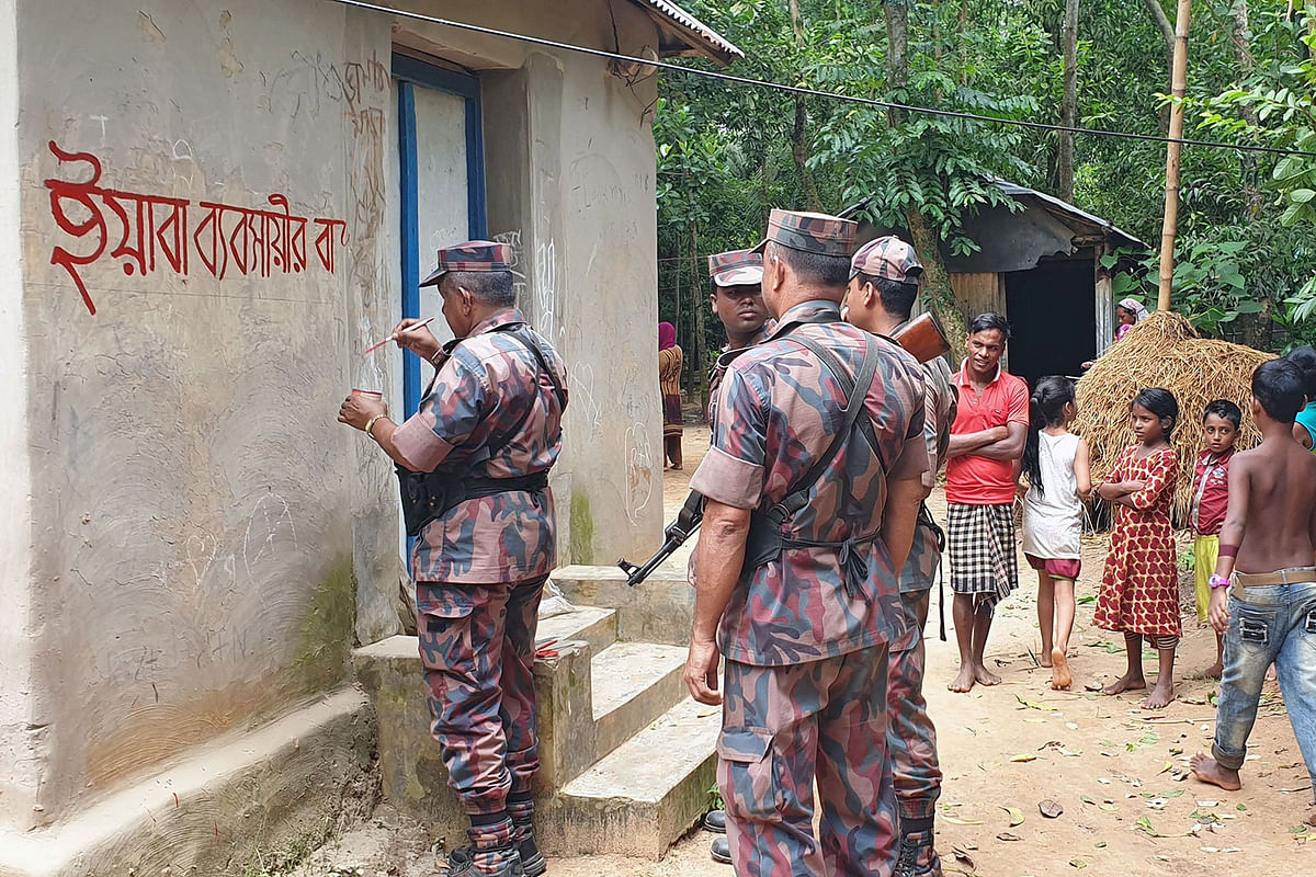 In this photo take on 23 September, 2019 shows Bangladesh border guards watching as a home allegedly belonging to a suspected drug trafficker is marked with red paint -- which reads `This is a house of a drug trafficker` -- in Akhaura. Photo: AFP
