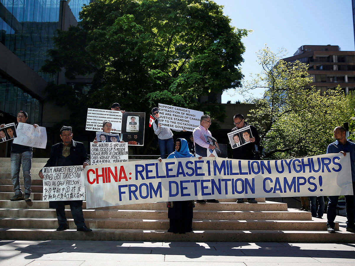 People hold signs protesting China`s treatment of the Uighur people during a court appearance by Huawei`s Financial Chief Meng Wanzhou, outside of British Columbia Supreme Court building in Vancouver, British Columbia, Canada, on 8 May 2019. Reuters File Photo