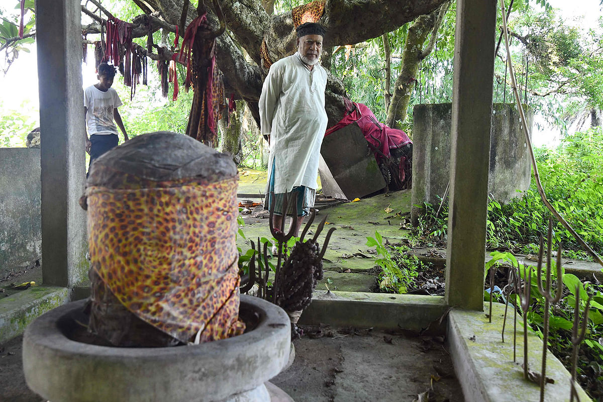 This photo taken 21 September 2019, shows Muslim caretaker Motibar Rahman, 73, standing by a shrine to the Hindu deity Shiva in Rangmahal village on the outskirts of Guwahati, the capital city of India’s northeastern state of Assam.  Photo: AFP