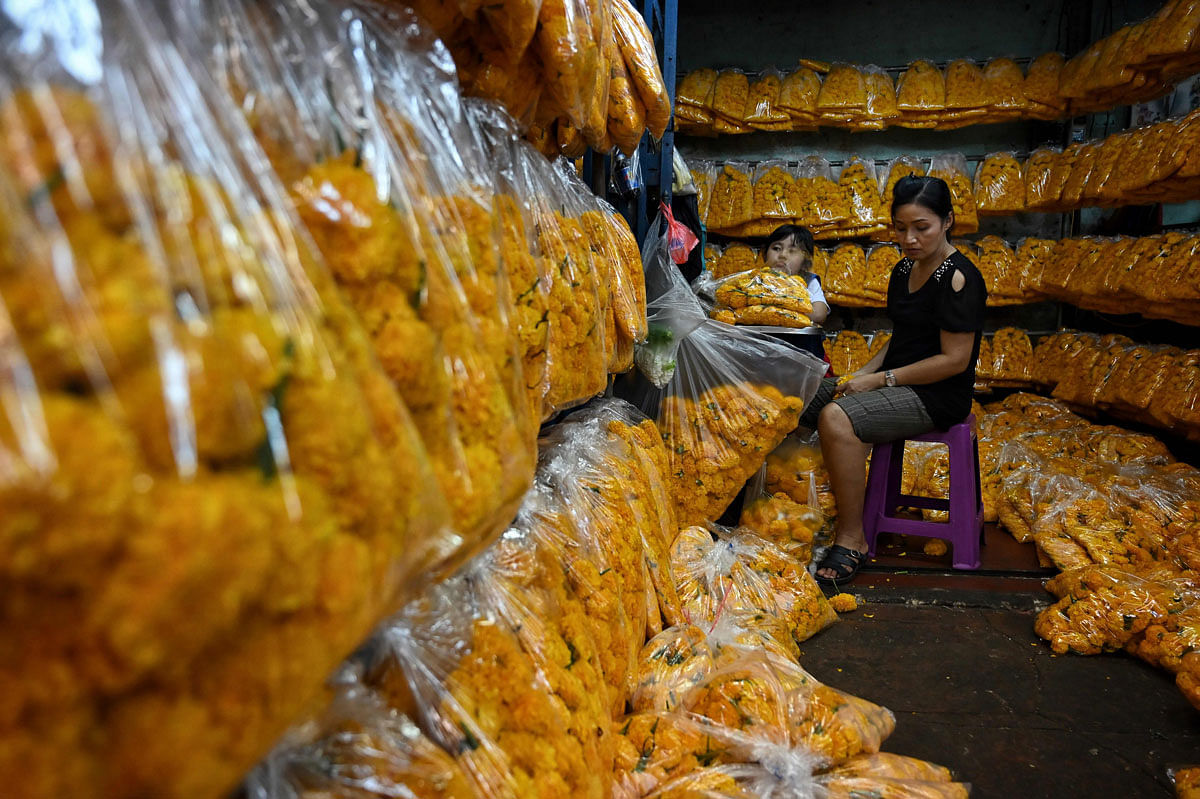 A woman prepares bags of chrysanthemums to sell at a flower market in Bangkok on 27 September, 2019. Photo: AFP