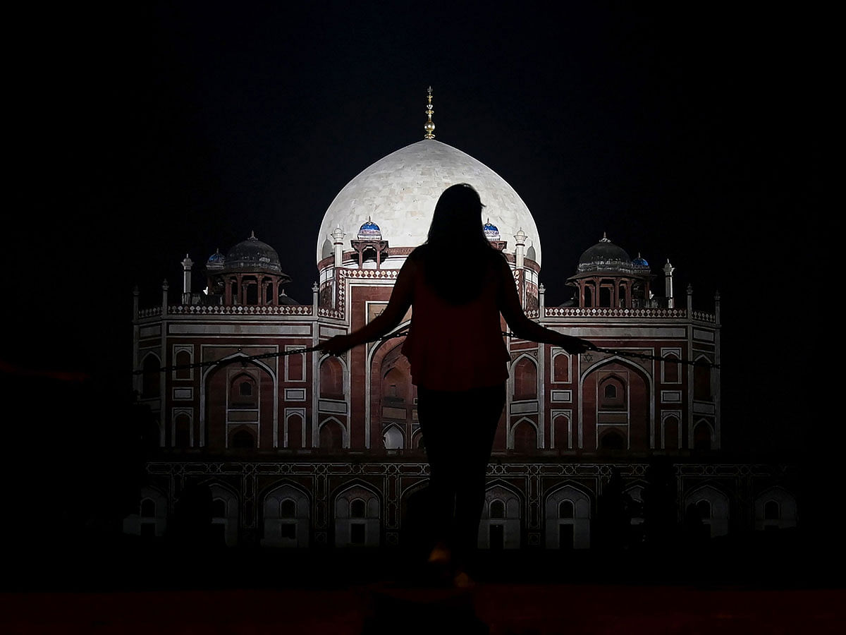 This photograph taken on 24 September 2019, shows a visitor standing at a fence in front of the illuminated Humayun`s Tomb, a 16th century Mughal monument, at night in New Delhi. Photo: AFP