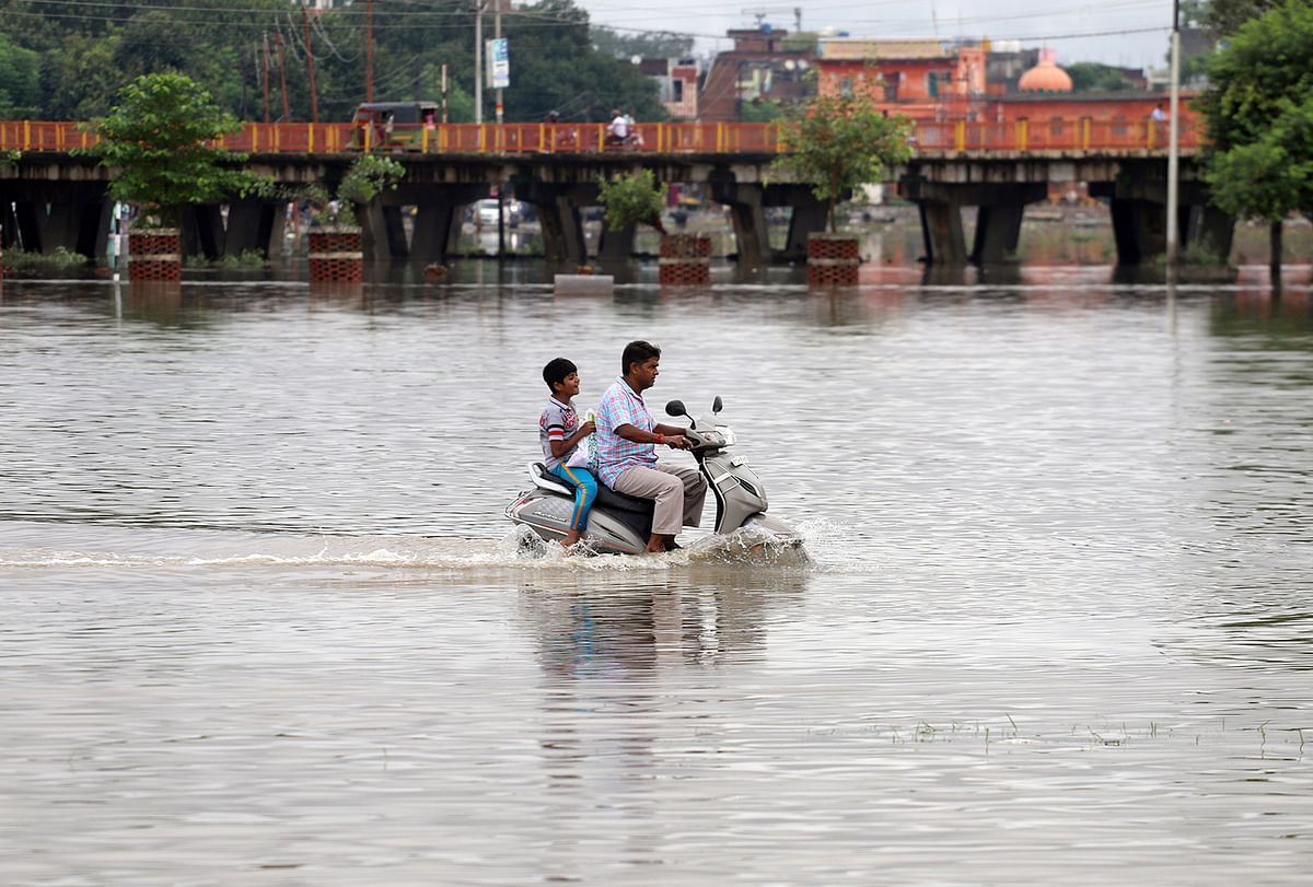 A man and a boy ride a scooter through a flooded road after heavy rains in Prayagraj, India, on 29 September 2019. Photo: Reuters