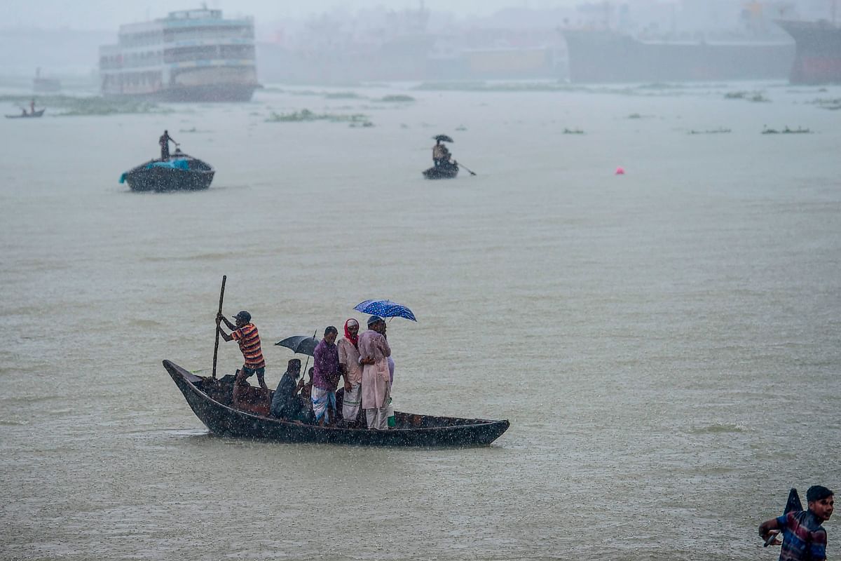 Men ride their boats under heavy rain in Buriganga river in Dhaka on 29 September 2019. Photo: AFP