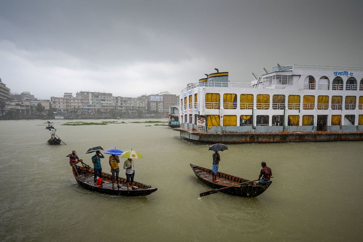 Men ride their boats under heavy rain in Buriganga river in Dhaka on 29 September 2019. Photo: AFP