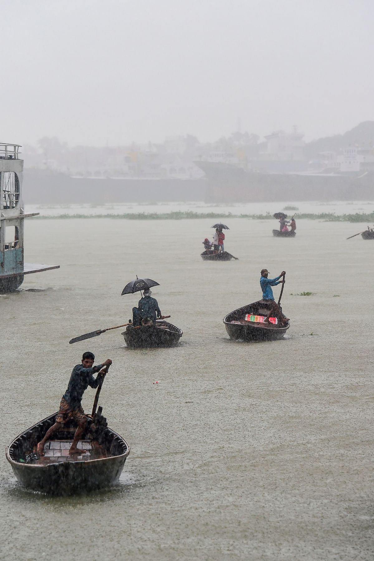 Men ride their boats under heavy rain in Buriganga River in Dhaka on 29 September, 2019. Photo: AFP