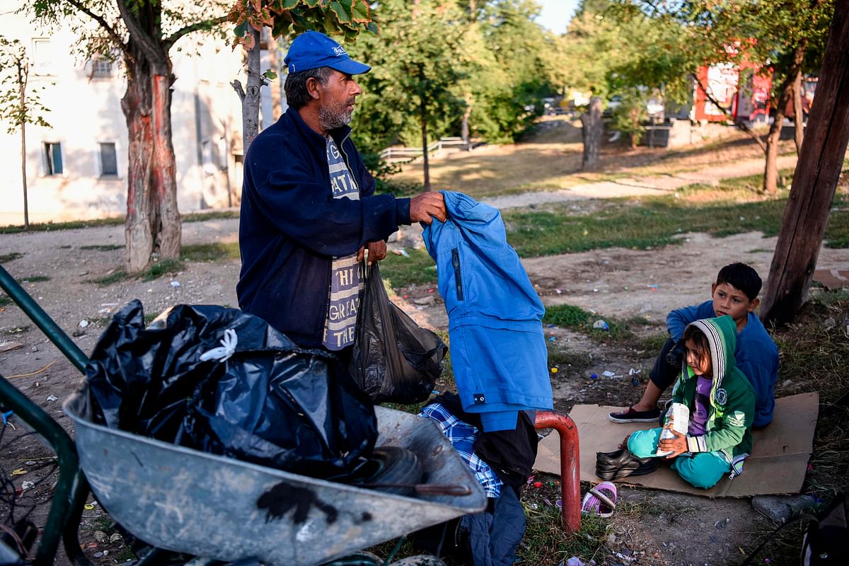 Bujar Maksuti arrange items that he found in the containers as his children look on, in Pristina, Kosovo, on 10 September. Photo: AFP