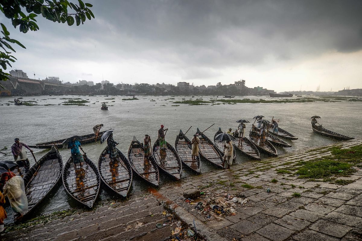 7Men stand on their wooden boats under heavy rain on the banks of Buriganga River in Dhaka on 29 September, 2019. Photo: AFP
