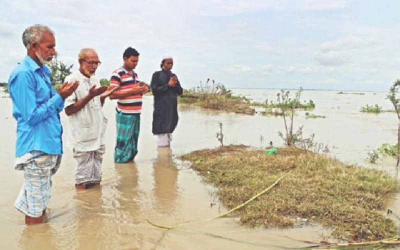Three siblings with a relative offer their last prayer before their mother`s grave which is likely to be eroded soon by river Padma in Goalanda, Rajbari on 27 September 2019. Photo: M Rashedul Haque