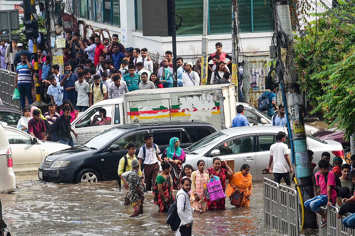 Bangladeshi pedestrians walk through a water-logged street following heavy rain in Dhaka on 1 October 2019. Photo: AFP
