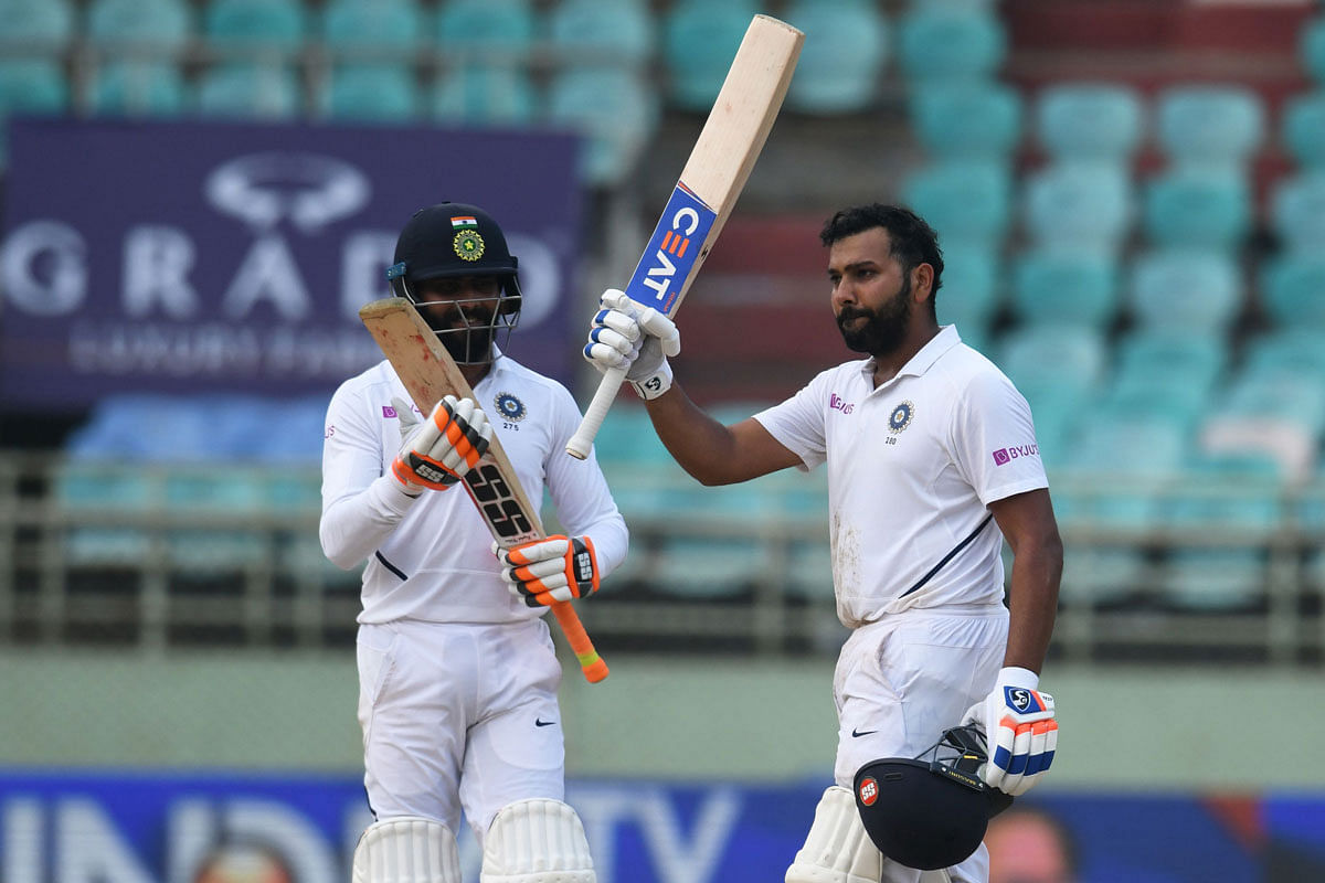 Indian cricketer Rohit Sharma (R) raises his bat after scoring a century (100 runs) during the fourth day`s play of the first Test match between India and South Africa at the Dr. Y.S. Rajasekhara Reddy ACA-VDCA Cricket Stadium in Visakhapatnam on Saturday. Photo: AFP