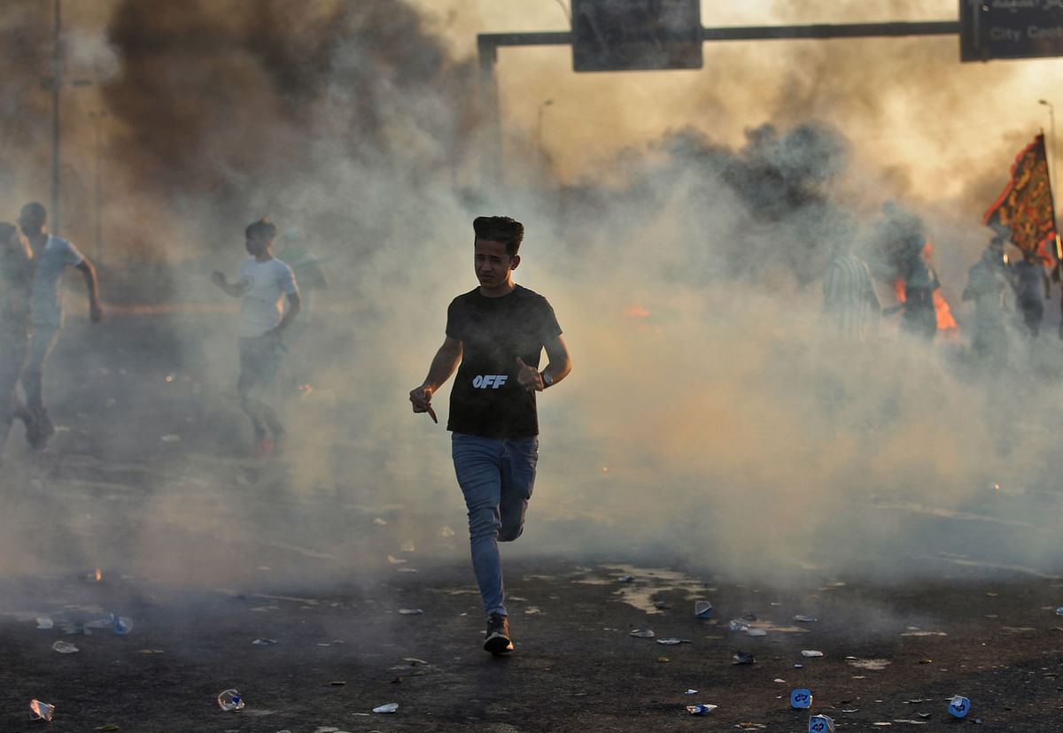 Iraqi demonstrators run amidst smoke from burning tyres during a demonstration against state corruption, failing public services, and unemployment, in the Iraqi capital Baghdad on 5 October 2019. Renewed protests took place under live fire in Iraq`s capital and the country`s south Saturday as the government struggled to agree a response to days of rallies that have left nearly 100 dead. Photo: AFP