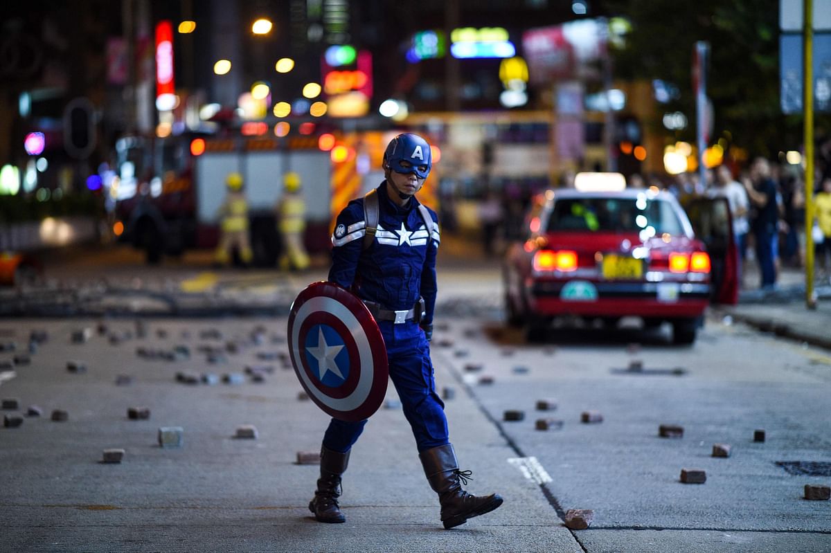 A man wearing a Captain America costume walks on a street as protesters and pedestrians gather near the Mong Kok police station in Hong Kong on 7 October 2019. Photo: AFP
