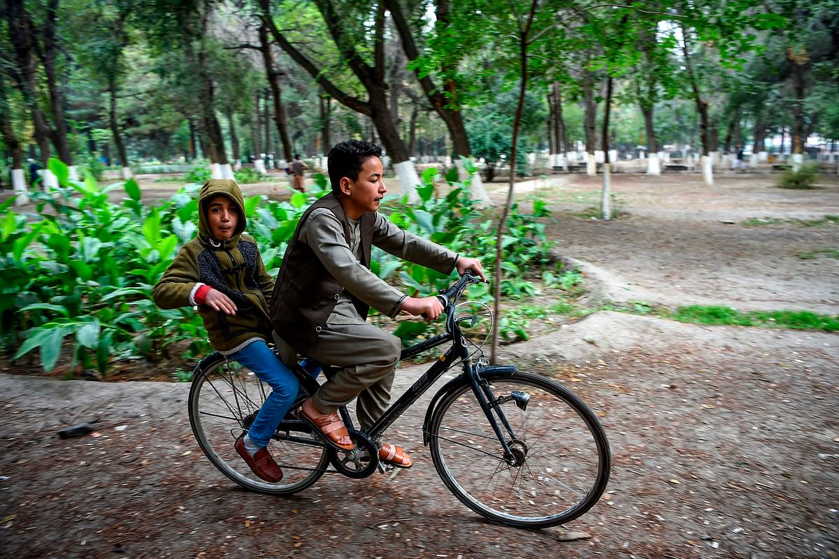 Youths look on as they ride a bicycle at the Shahr-e-Naw Park in Kabul on 6 October 2019. Photo: AFP