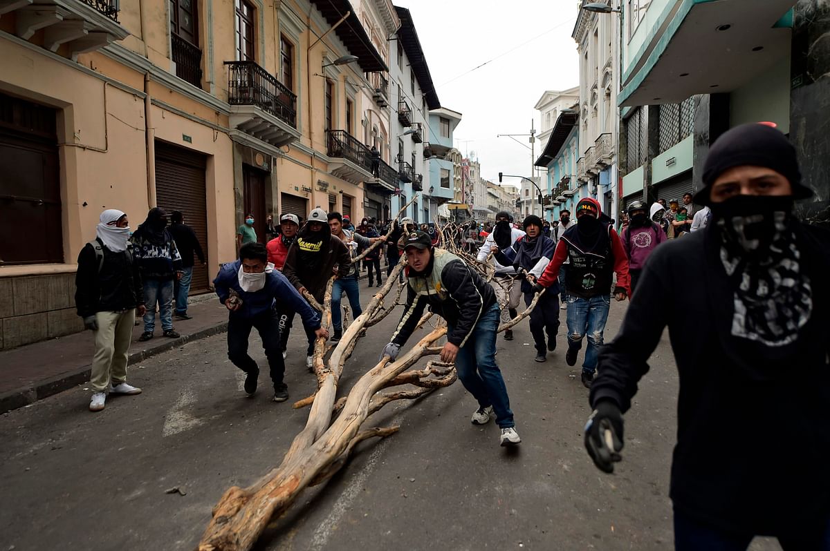Demonstrators push a dried tree branch along a street in Quito during clashes with riot police on 8 October 2019 following days of protests against the sharp rise in fuel prices sparked by authorities` decision to scrap subsidies. Photo: AFP