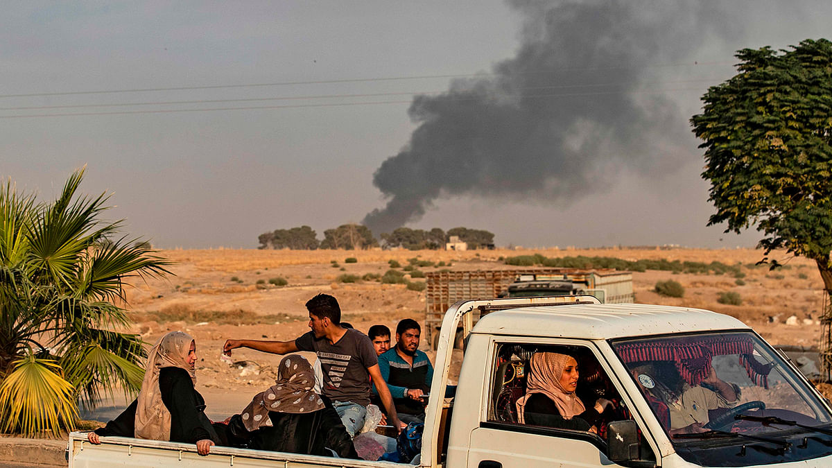 Civilians ride a pickup truck as smoke billows following Turkish bombardment in the northeastern town of Ras al-Ain in Syria`s Hasakeh province along the Turkish border on 9 October 2019. Turkey launched an assault on Kurdish forces in northern Syria with air strikes and explosions reported along the border. Photo: AFP