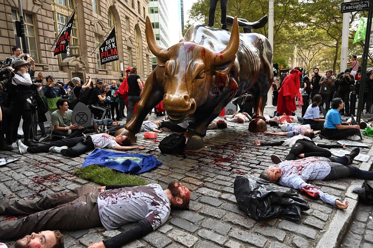 Protestors covered in fake blood gather around the Wall Street Bull during an “Extinction Rebellion” demonstration in New York on 7 October 2019. Photo: AFP